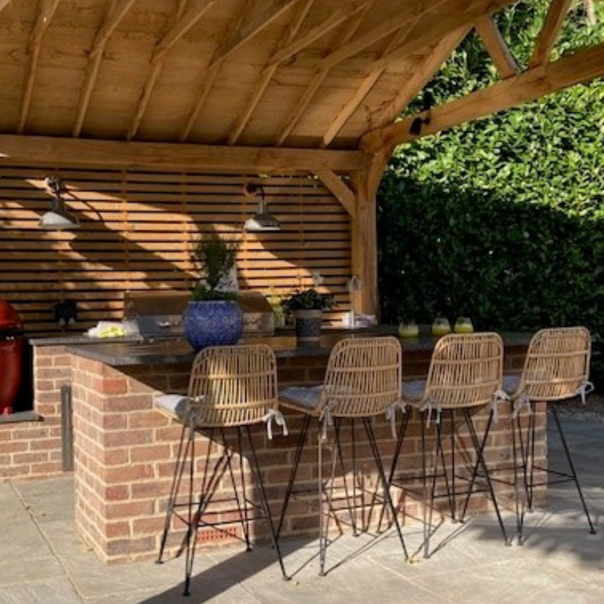 An outdoor kitchen with a brick breakfast bar under a bespoke oak pergola