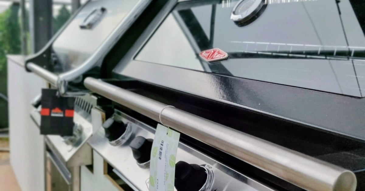 Built-in gas grill integrated into an outdoor kitchen counter, surrounded by stainless steel cabinetry