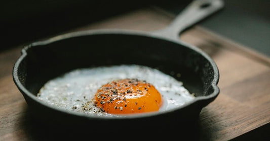 Cast iron skillet with golden roast potatoes on an outdoor grill grate, ready to serve