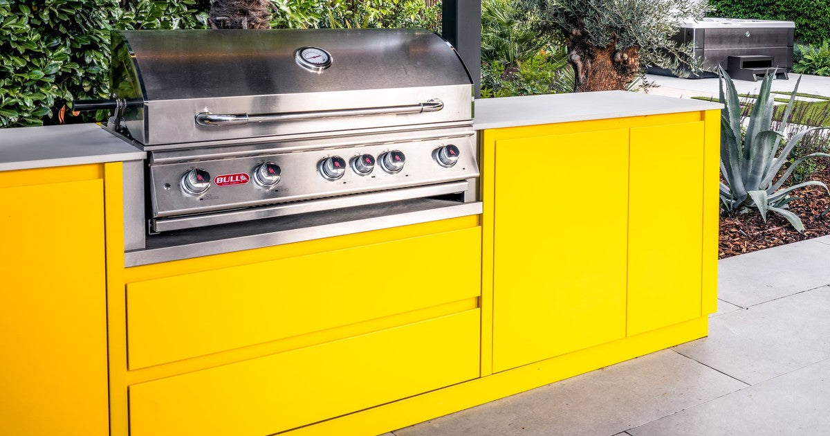 Block-built outdoor kitchen with built-in BBQ grill, stainless steel doors and porcelain worktop in a Surrey garden
