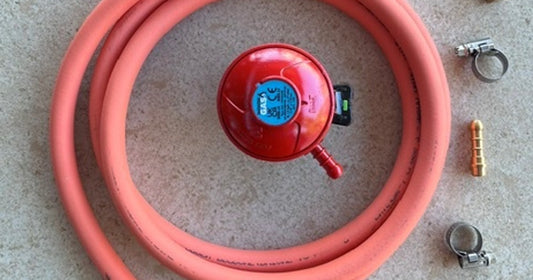 LPG gas bottle connected to a Bull BBQ with regulator and hose attached, outdoors on a patio