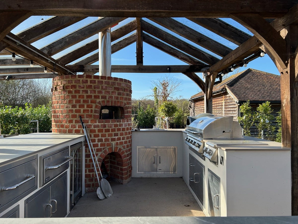 Outdoor kitchen positioned safely near a garden fence, showing clearance from boundary and built-in grill