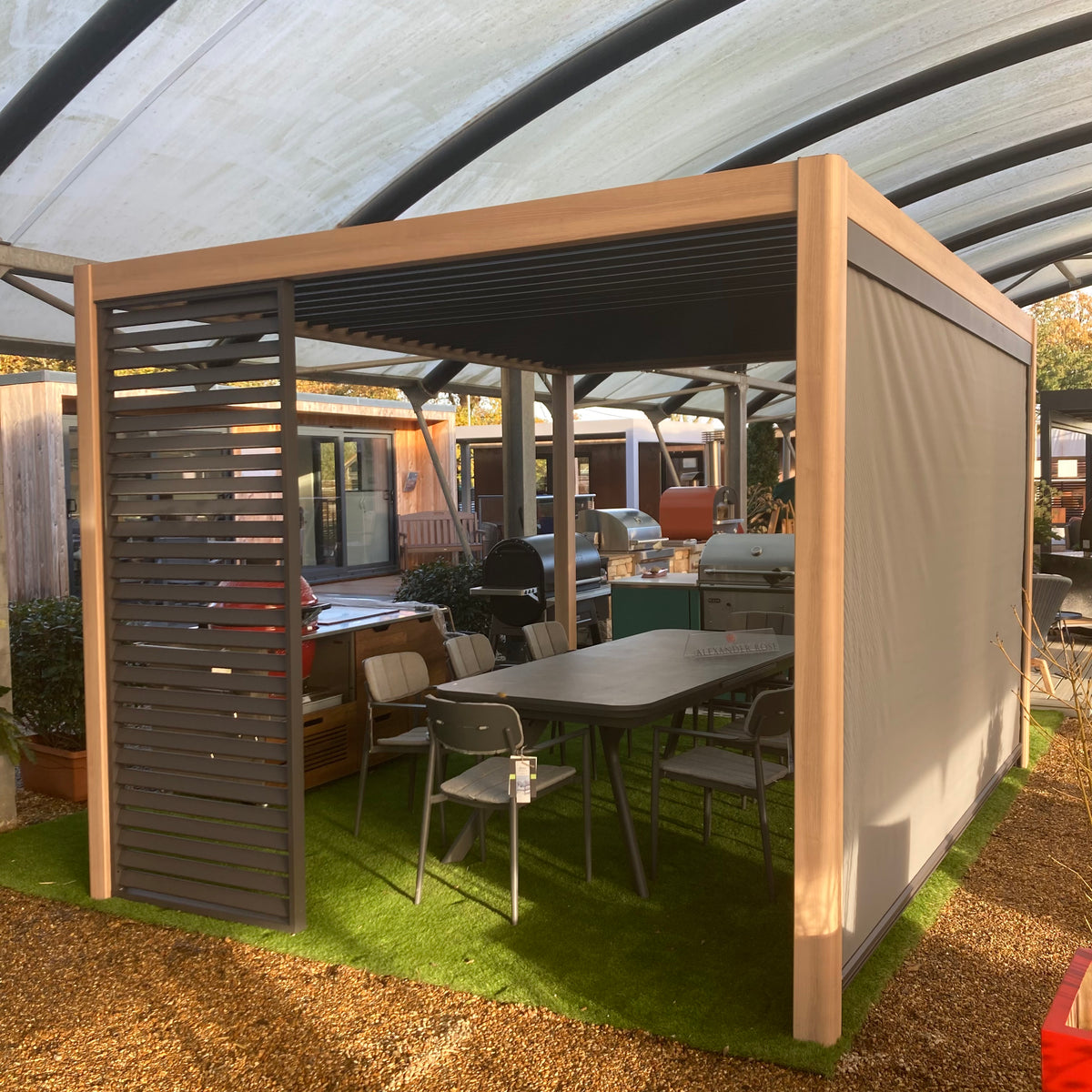 An aluminium pergola with side screens over a dining table and grill at our showroom